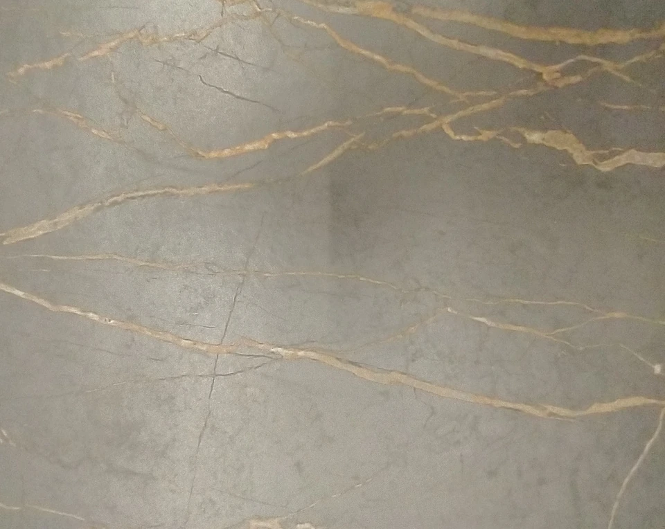 Fotografía de cuarzo compuesto gris con vetas cálidas doradas y reflejos de la superficie.