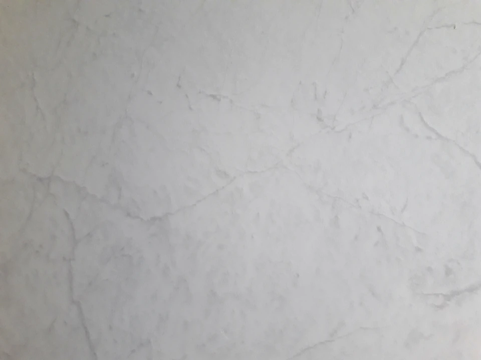 Fotografía de una superficie de mármol claro con vetas grises sutiles.