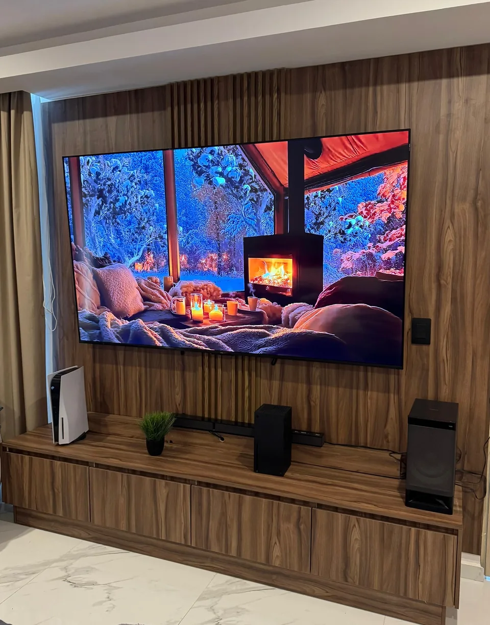 Centro de TV con panelado vertical en tono madera y mueble bajo de almacenamiento.